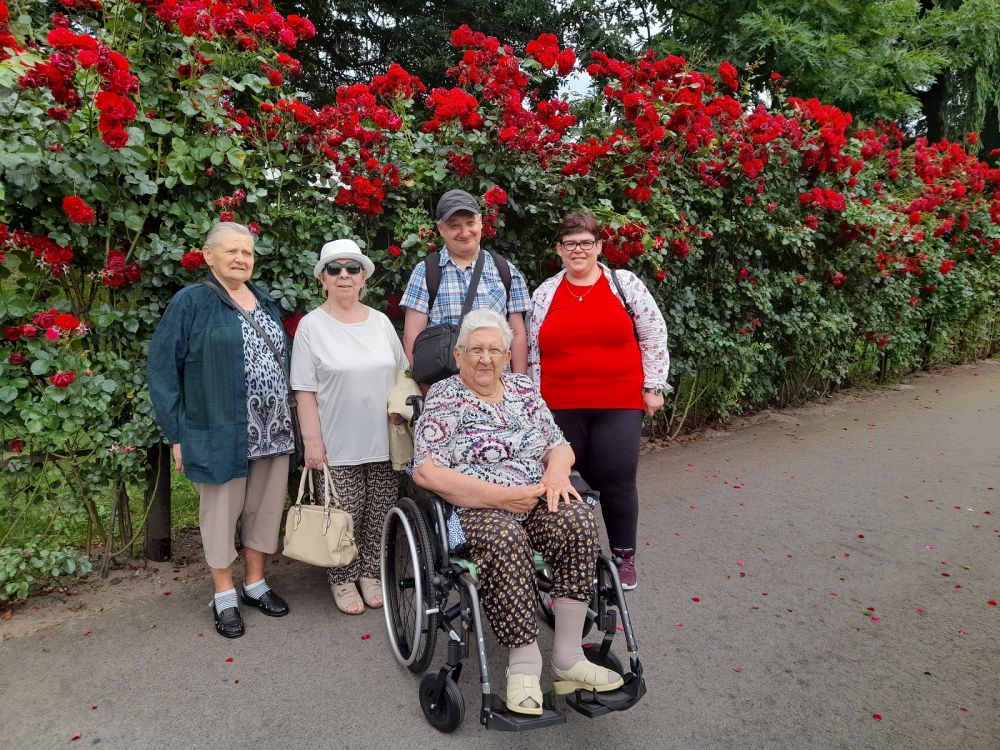 Zdjęcie grupowe uczestników wycieczki z różami w tle