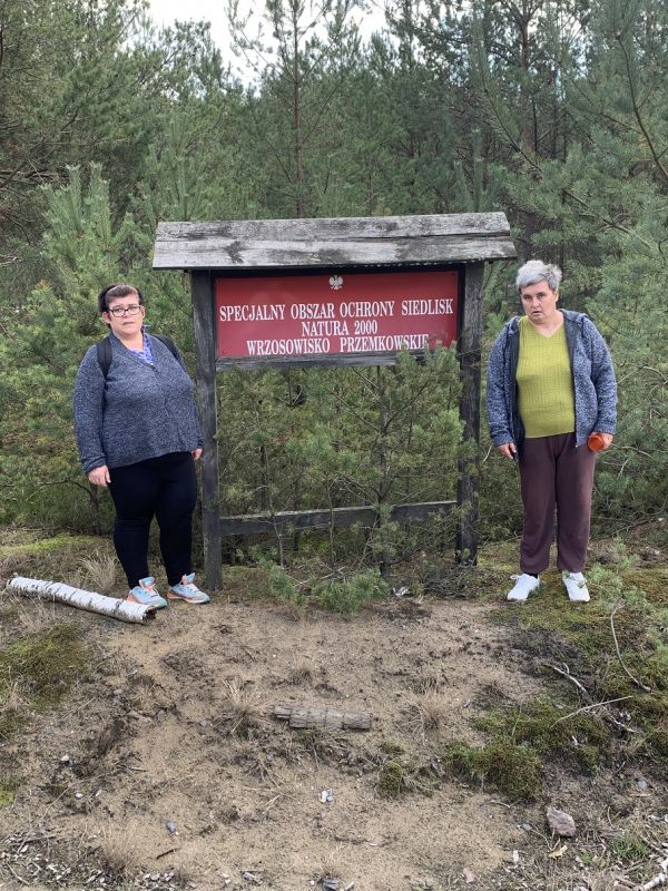Miszkanki stoją po bokach tablicy - na tablicy napis Specjalny Obszar Ocgrony Siedlisk Natura 2000 Wrzosowisko Przemkowskie 