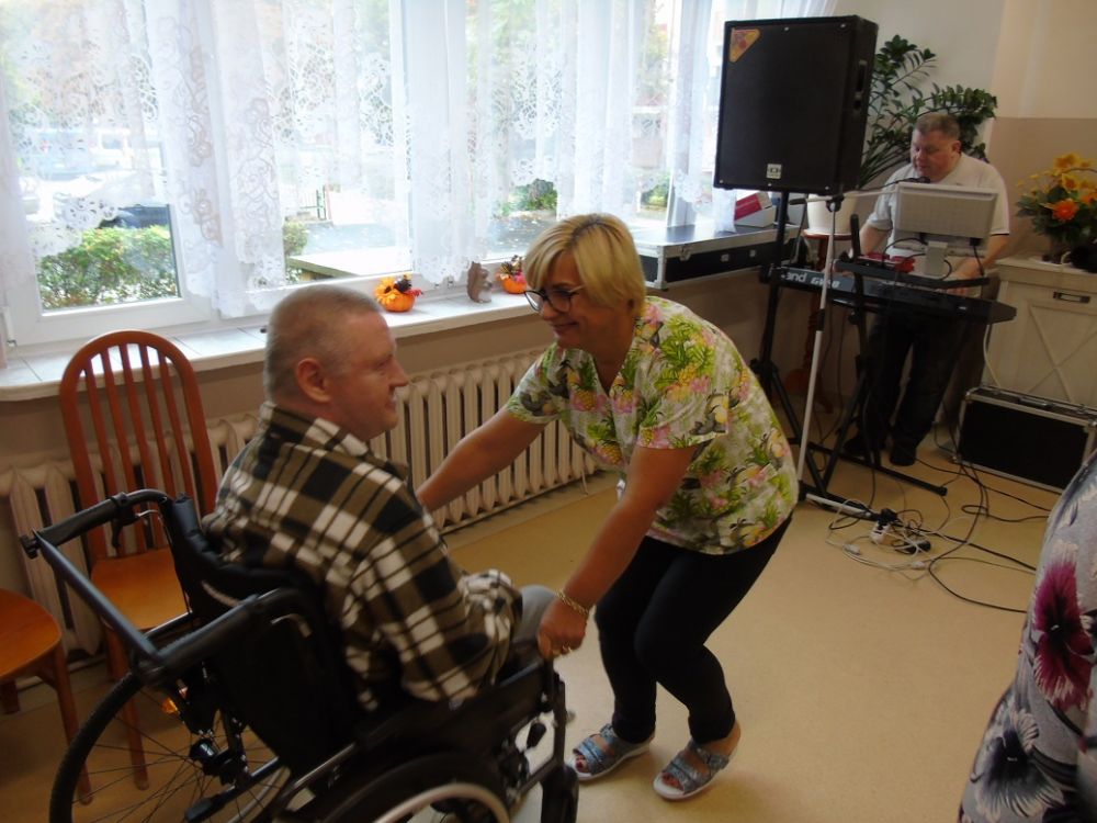 Opiekun tańczący z mieszkańcem na wózku inwalidzkim