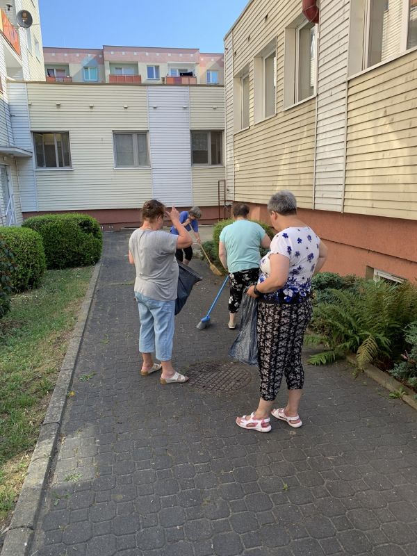 Mieszkanki zamiatają chodnik przed budynkiem pralni
