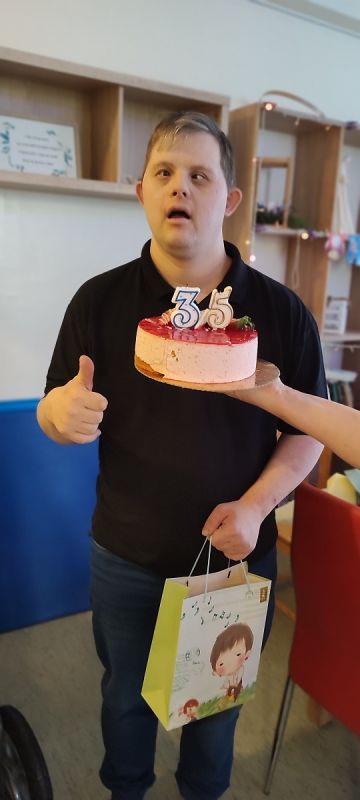 Podopieczny trzyma tort urodzinowy z cyfrą 35.