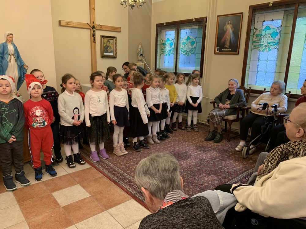 grupa dzieci śpiewa pastorałki w kaplicy dla mieszkańców 