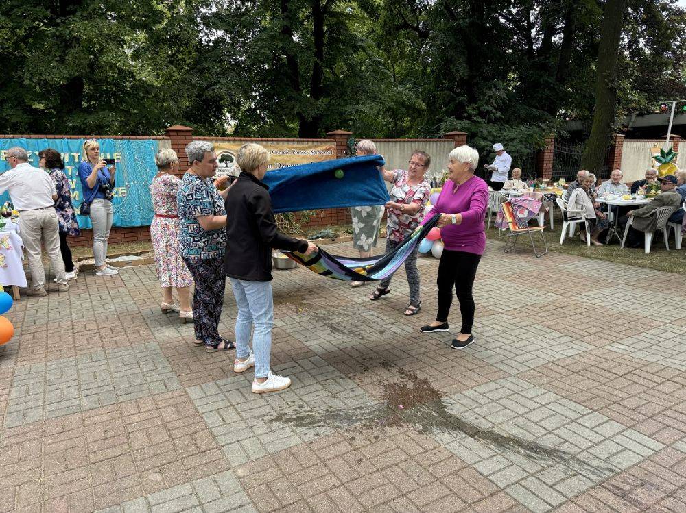 Uczestnicy stoją z ręcznikami i przerzucają balony z wodą. 